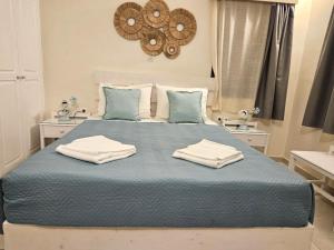 a bedroom with a blue bed with two towels on it at Ersi Villas in Firostefani