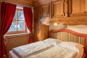 a bedroom with a bed with red curtains and a window at PLOSE Parkhotel & Residence in Bressanone +127 photos