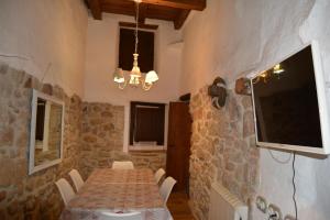 a dining room with a table and a tv on a stone wall at El Encantodemora in Mora de Rubielos