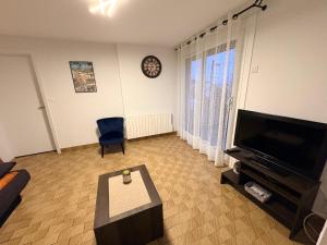 a living room with a flat screen tv and a blue chair at Abéane in Châtel-Guyon