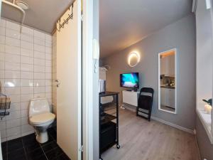 a bathroom with a toilet and a sink and a television at Cozy Central Studio by the Bus Station in Bergen +8 photos