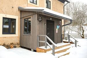 a small building with a door in the snow at Zeit Apartments in Līgatne