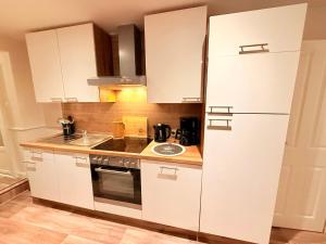 a kitchen with white cabinets and a refrigerator at Ferienhaus Teenös in Hinte