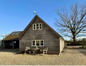 a barn with two chairs and a table in front of it at Luxurious Country Barn in Baughurst