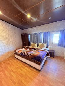 a bedroom with a large bed with blue curtains at Nature Nook's Kufri in Kūfrī