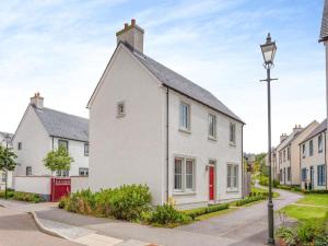 a white house with a red door on a street at One The Loan in Inverness