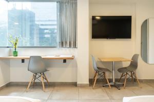 a meeting room with two chairs and a table and a tv at Hotel Bambu Milla De Oro in Medellín