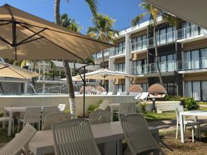 an outdoor patio with tables and chairs and umbrellas at Coco Blue a New Beach Resort in La Libertad