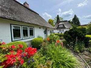 a white house with flowers in the yard at Emmis-Ferienhaus in Dörpling