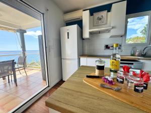a kitchen with a table with a bottle of wine at Horizon Doré Appt avec piscine - vue sur mer in Gourbeyre