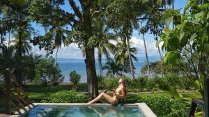 a woman sitting in a pool with the ocean in the background at Playa Cativo Lodge in Esquinas