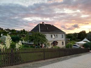 a white house with a black roof behind a fence at Ferienwohnung Schneeberg in Schneeberg