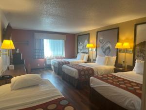 a hotel room with three beds and two lamps at Super 8 by Wyndham Las Vegas in Las Vegas