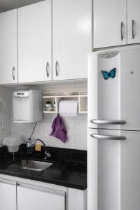 a kitchen with a sink and a refrigerator with butterflies on it at KOKIRA Apê in Campinas