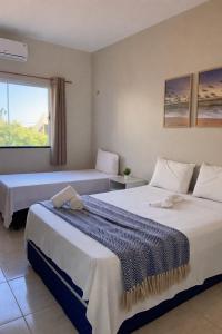two beds in a room with a window at Praieiro pousada in Prea