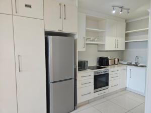 a white kitchen with white cabinets and a refrigerator at Breakers Resort Apartment 314 in Durban