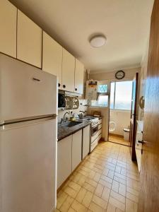 a kitchen with a white refrigerator and a tile floor at Depto Frente Al Mar, Edificio Iskofema II in Miramar