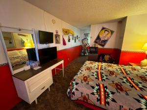 a bedroom with a bed and a desk with a television at Stagecoach 66 Motel by Capital O in Seligman