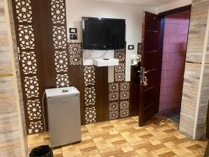 a bathroom with a toilet and a tv on a wall at Shaheen hotel in Suez