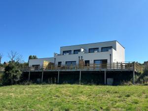 a white house with a deck on a hill at La Vallée des Biches G2 in Saint-Martin-Boulogne