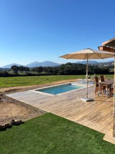 a patio with an umbrella and a swimming pool at Bergerie du Riccio avec piscine privée in Cauro