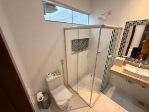 a bathroom with a toilet and a glass shower at Casa com piscinas paragominas in Paragominas +27 photos