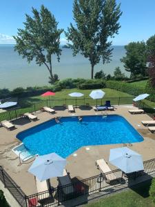 a swimming pool with umbrellas and chairs and the ocean at L'Auberge Du Lac St-Pierre in Trois-Rivières