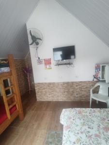 a bedroom with a tv on a wall with a fan at Chalé Arizona in São Roque