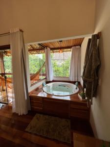 a bath tub in a room with a window at Chalés Vale das Pedras in Venda Nova do Imigrante