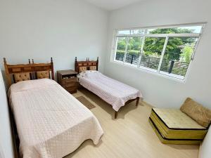a bedroom with two beds and a window at Nogueira Home in Passa Quatro