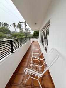 two white chairs sitting on the balcony of a house at Nogueira Home in Passa Quatro