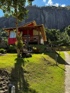 a house on a hill with a mountain in the background at Chalés Vale das Pedras in Venda Nova do Imigrante