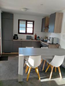 a kitchen with a table and two white chairs at Villa de l Eyre in Salles +5 photos