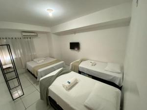 a hotel room with three beds and a mirror at its hotel in Itapetinga