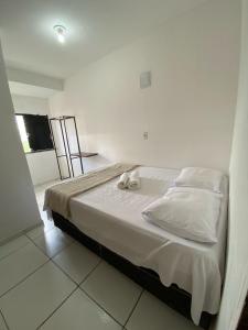 a bedroom with a bed with white sheets and pillows at its hotel in Itapetinga