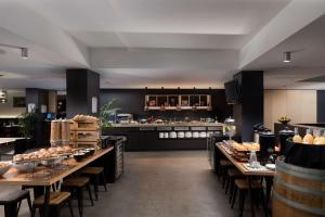 a restaurant with tables and chairs and a kitchen at Rydges Mount Panorama Bathurst in Bathurst