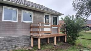 a wooden bench on the side of a house at Sunrise in Hollum +2 photos