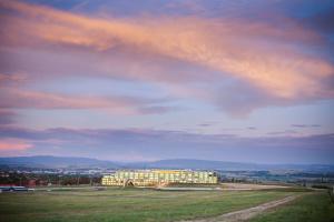 a building in a field under a cloudy sky at Rydges Mount Panorama Bathurst in Bathurst