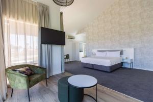 a bedroom with a bed and a chair and a table at Rydges Formosa Auckland Golf Resort in Auckland