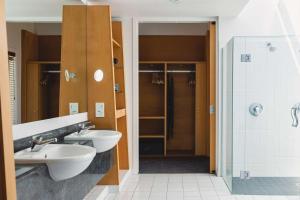 a bathroom with two sinks and a shower at Rydges Formosa Auckland Golf Resort in Auckland +43 photos