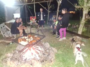 a group of people standing around a grill with a dog at Domki bungalowe nr 8 in Stosrow
