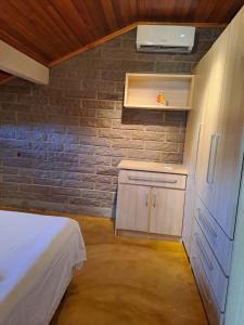 a small bedroom with a bed and a brick wall at Loft 73 in Bento Gonçalves
