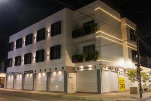 ein weißes Gebäude mit Türen und Fenstern bei Nacht in der Unterkunft MARUVA Hotel Ejecutivo in Tecomán
