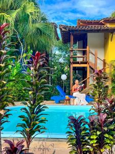 a woman sitting by a pool next to a house at Flat Barra in Barra Grande