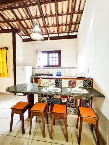 a kitchen with a counter with four chairs and a table at Flat Barra in Barra Grande
