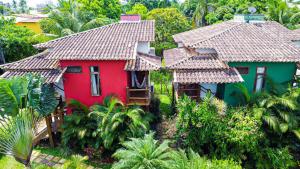 a red and green house in a garden with trees at Flat Barra in Barra Grande