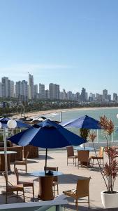 a group of chairs and tables with umbrellas on a beach at Flat em Cabo Branco - Blue Sunset in João Pessoa