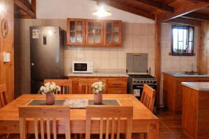 a kitchen with a wooden table and a refrigerator at Refugio araucano - Lican Ray in Licán Ray