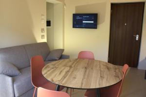 a living room with a wooden table and pink chairs at Appartamento PALE 2 posti letto in Pale