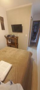 a bedroom with a bed and a flat screen tv at Casa Container em Monte Verde - 800m do Centro in Monte Verde